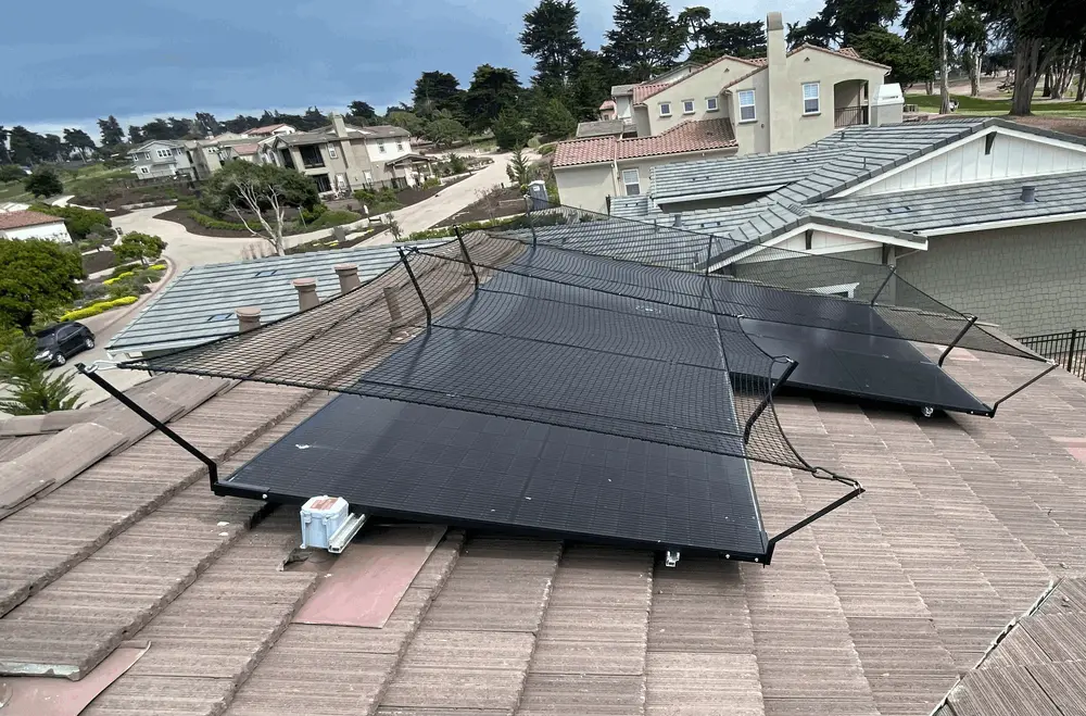 Protective mesh installed above solar panels on a tiled residential roof